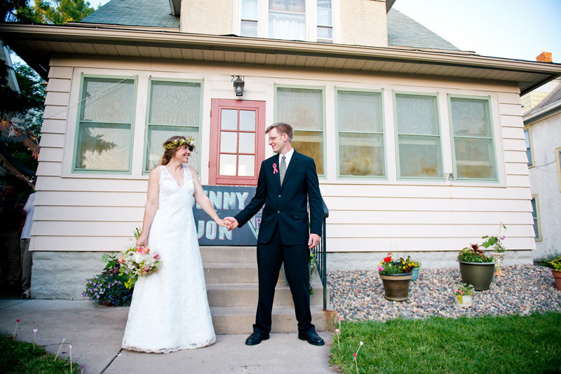 newlyweds post in front of house holding hands