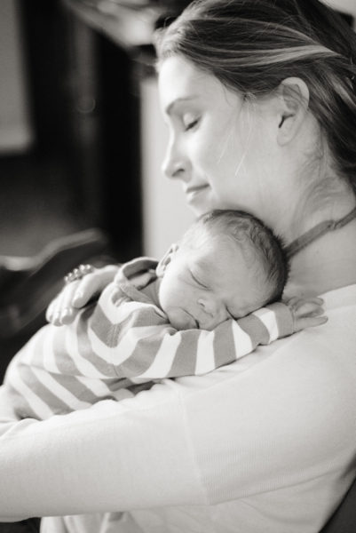 mom cuddling newborn with eyes closed