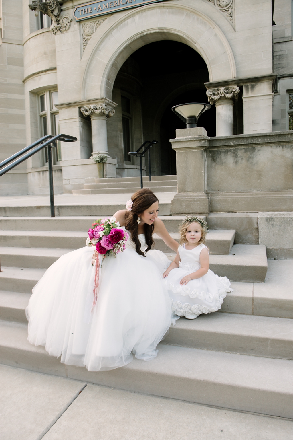 bride and flower girl sitting on steps together
