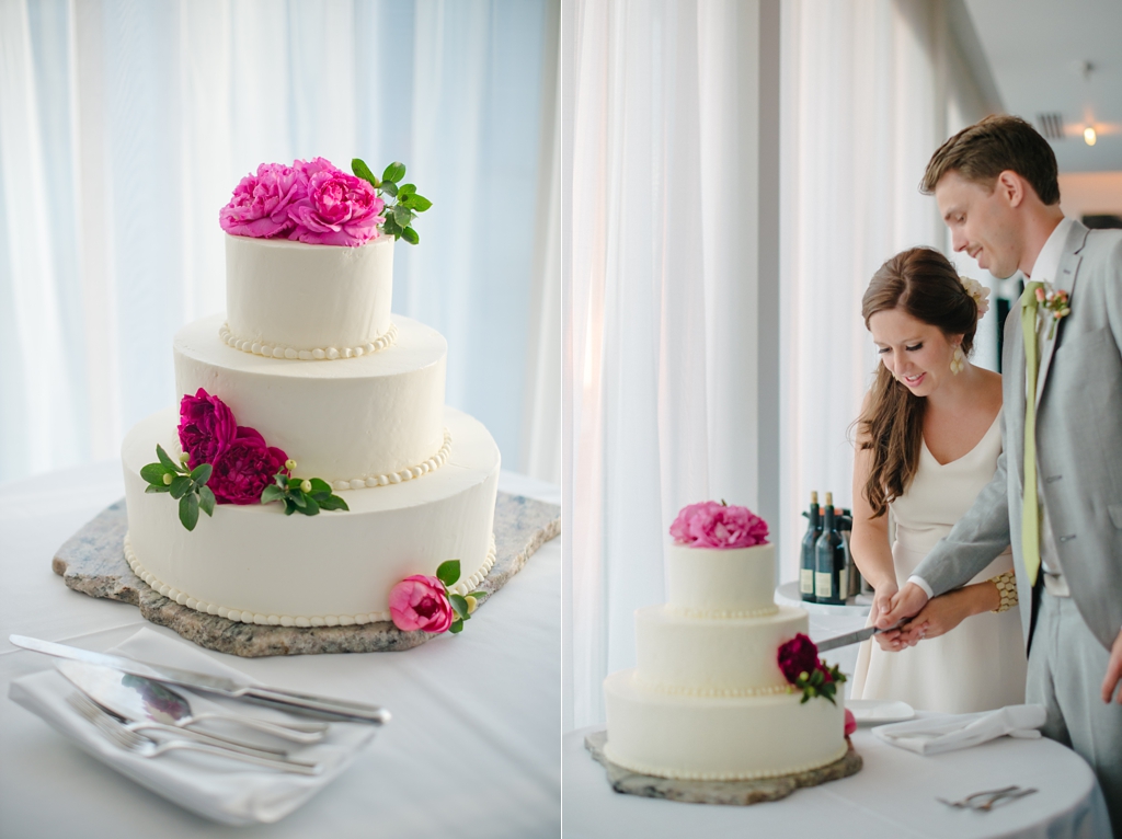 bride and groom cut wedding cake with pink flowers