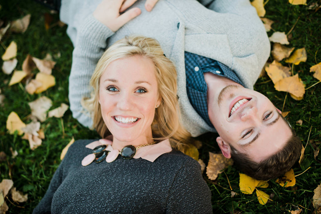couple laying in grass and leaves minneapolis engagement session
