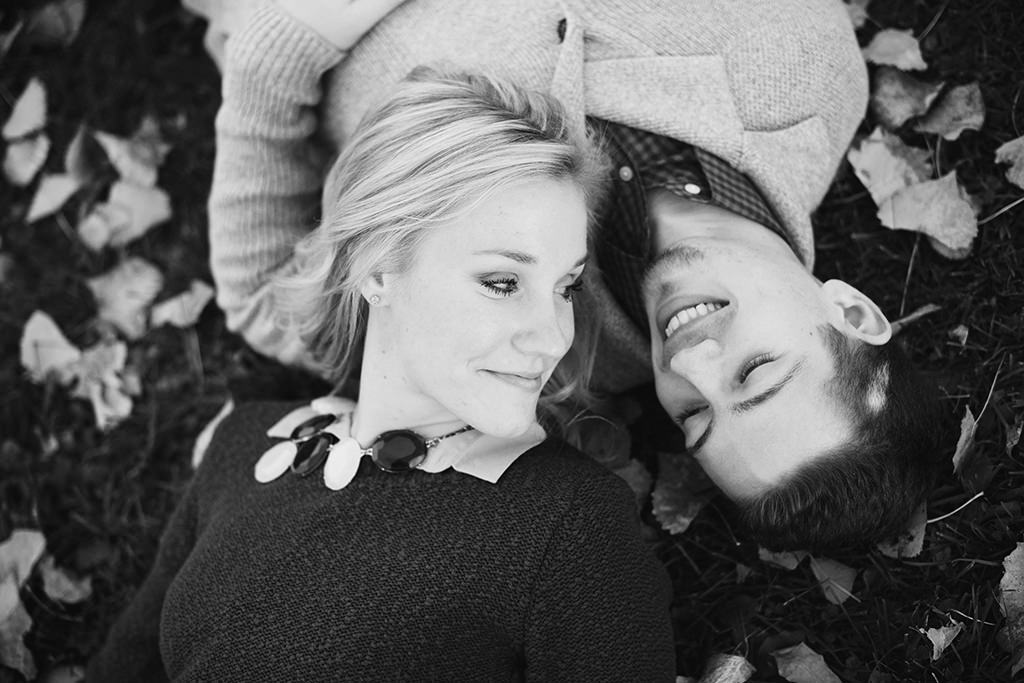 couple laying in grass black and white