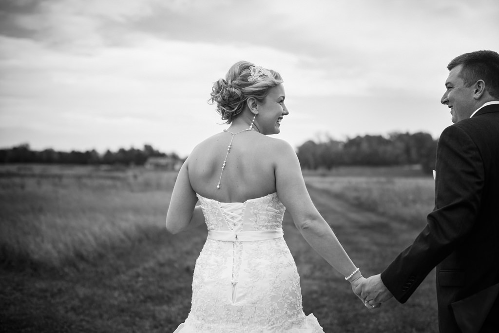 bride and groom walk together in field