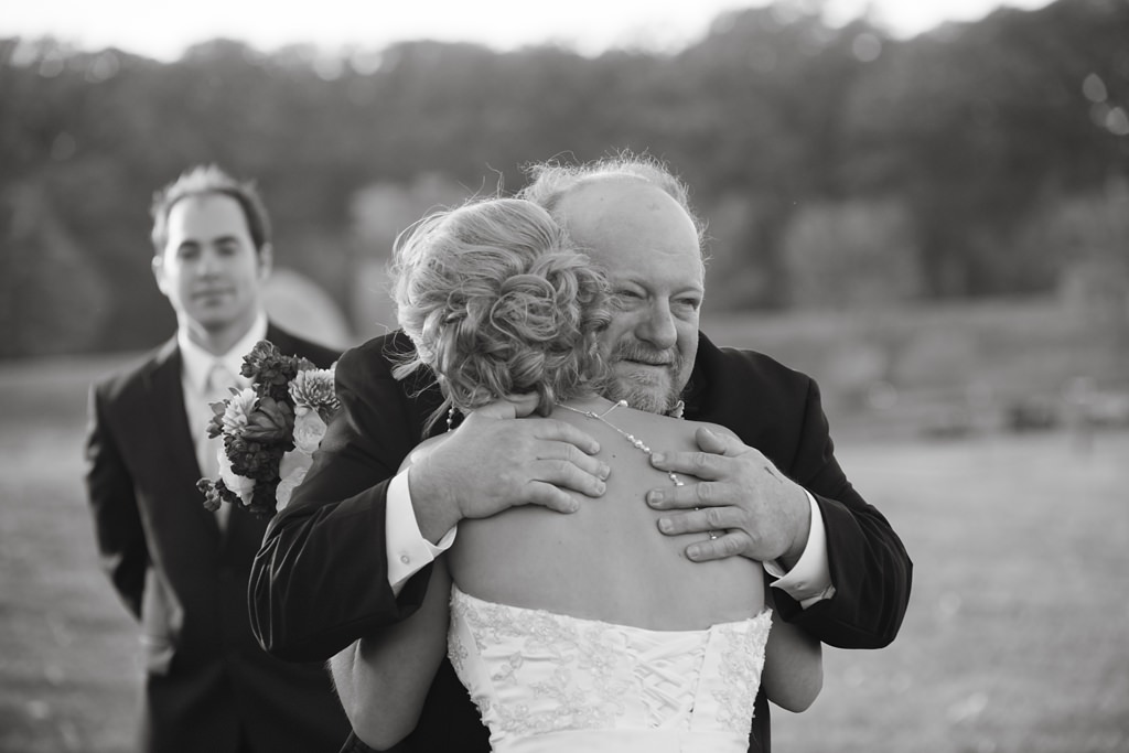 bride hugs father at outdoor wedding