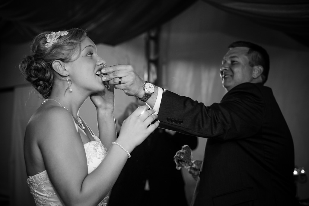 groom feeds bride cake at reception