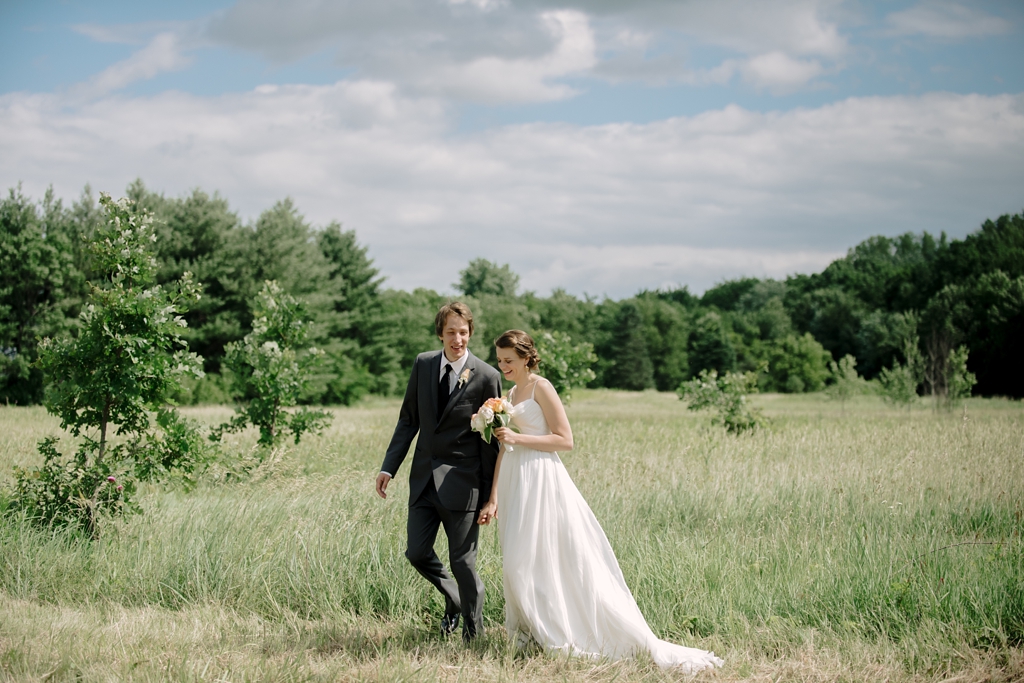 bride and groom walking through midwest field