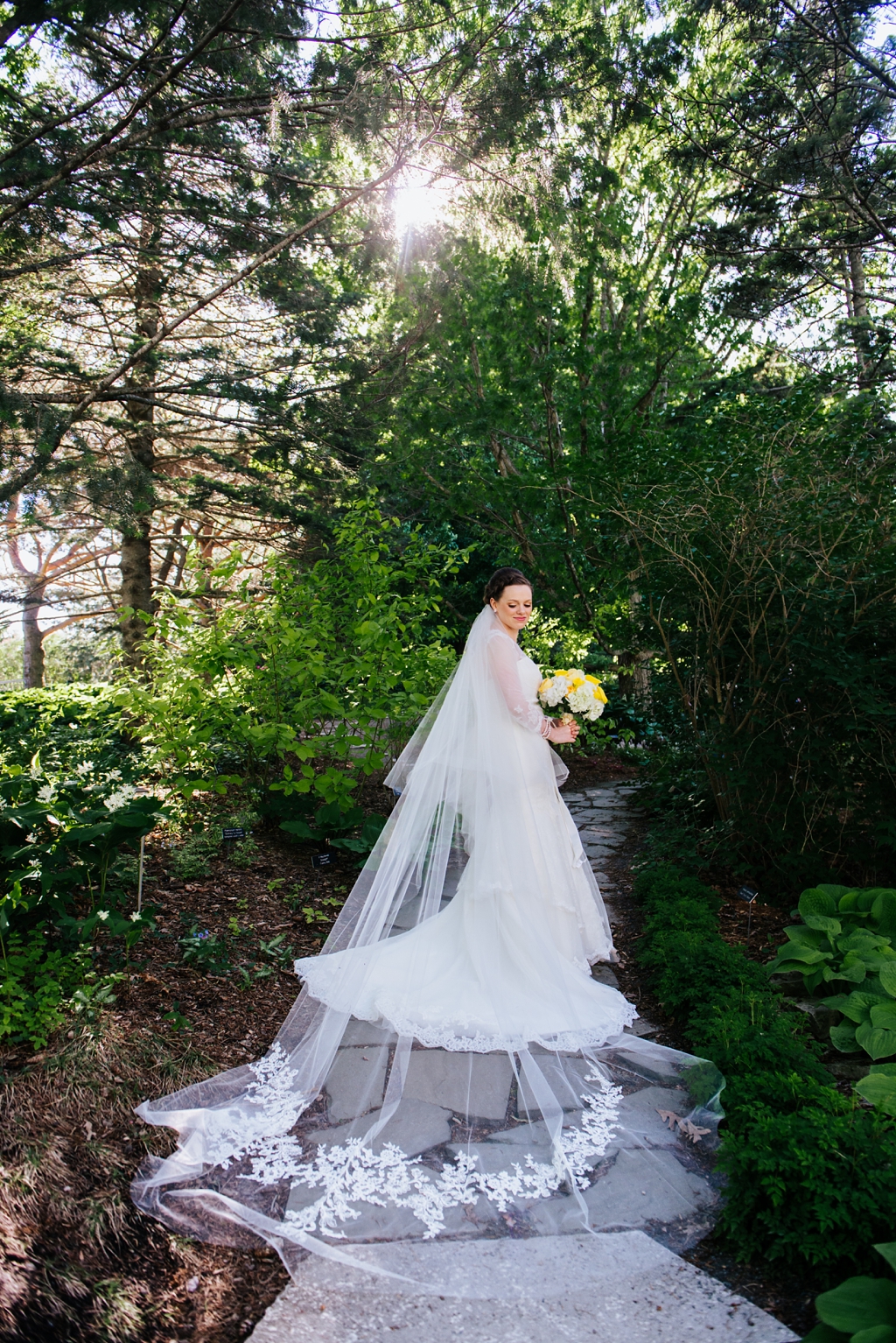 bride with long train posed on minnesota arboretum path