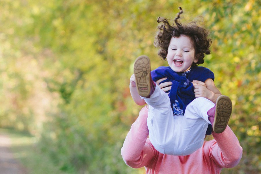 mom tossing daughter into air during fall family session