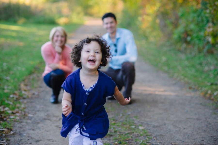 girl running toward camera with parents in background