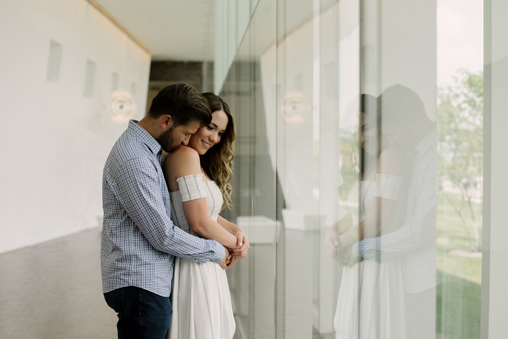 Couple hugging in front of the window for their museum engagement photos