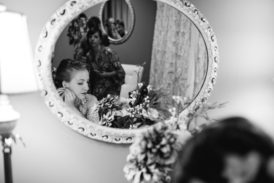 bride putting on earrings in black and white