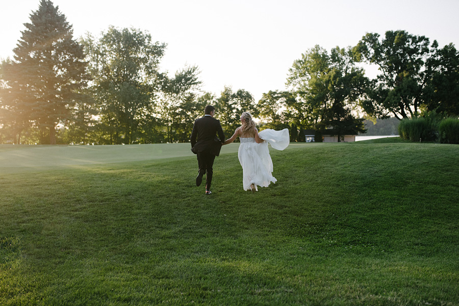 bride and groom running during sunset