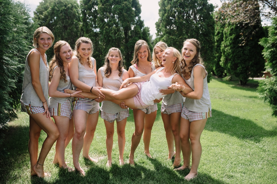 bridesmaids holding bride outside and laughing