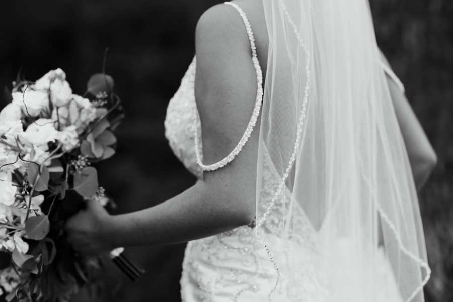 black and white photograph of back of bride's dress, and bouquet