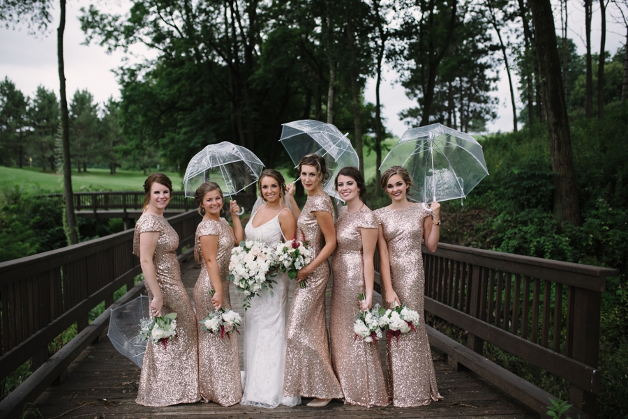 bride and bridesmaids holding umbrellas in the rain