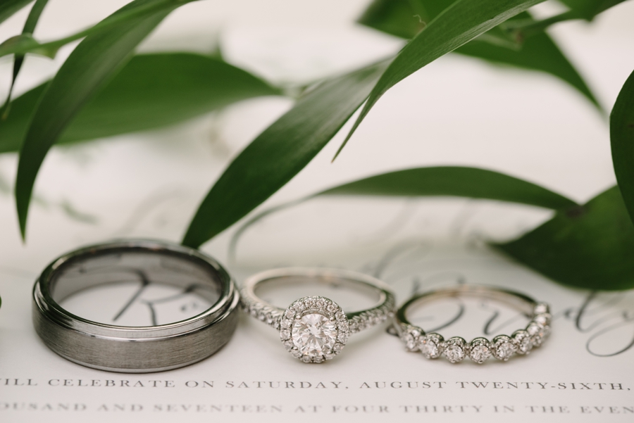 wedding rings on wedding invitation with greenery