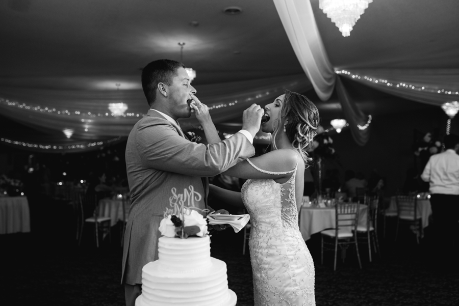 black and white bride and groom feeding each other cake