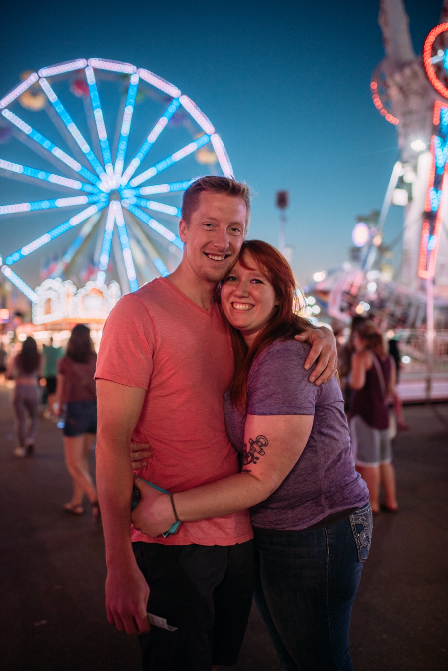 Couple hugging at minnesota state fair with ferris wheel in the background