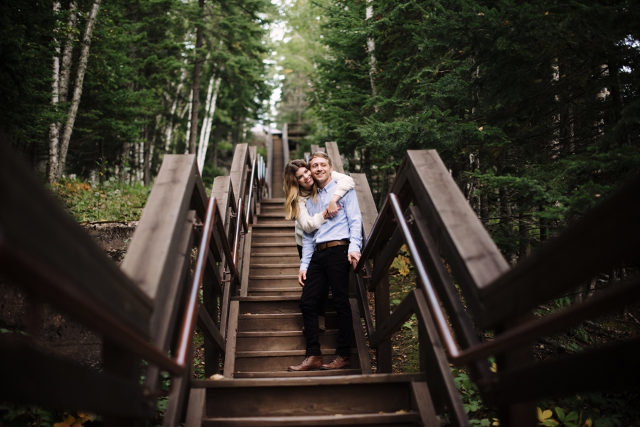 couple embrace on stairs in woods of northern minnesota