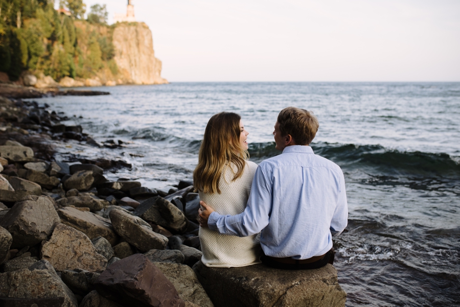 couple sit on rocks beside lake superior