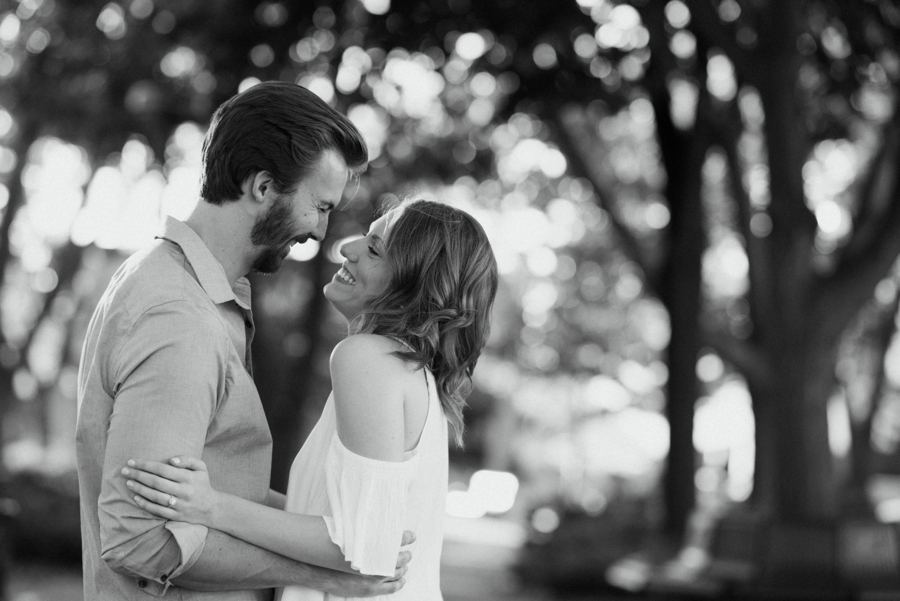 Happy couple hugging in park during their engagement photos mn