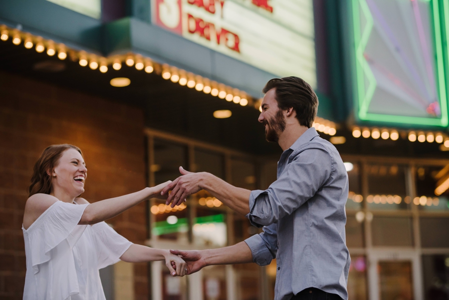 Couple dancing in front of Movie theater entrance with lights on 