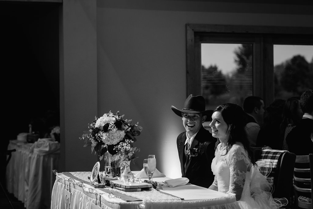 bride and groom laugh at their table during reception 