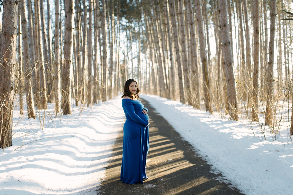 pregnant woman in blue poses in minnesota woods