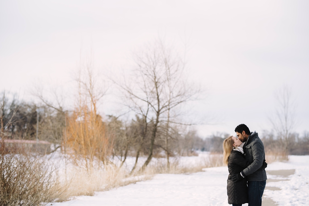 engaged couple kisses in the snow at Lake of the Isles engagement session