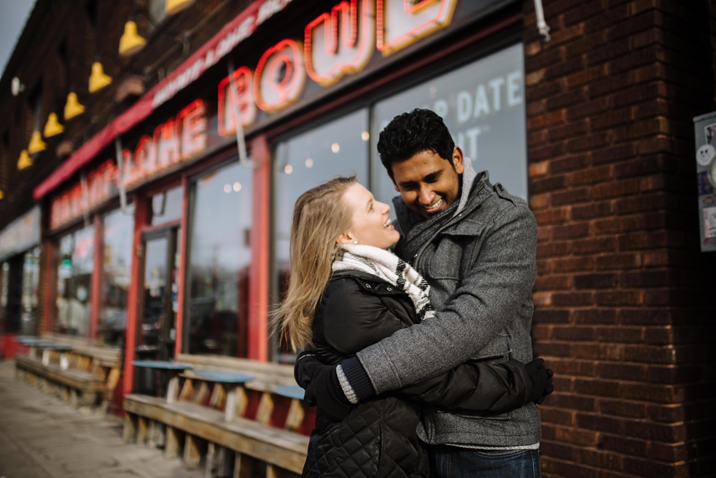 couple hugs in front of Bryant Lake Bowl neon sign minneapolis