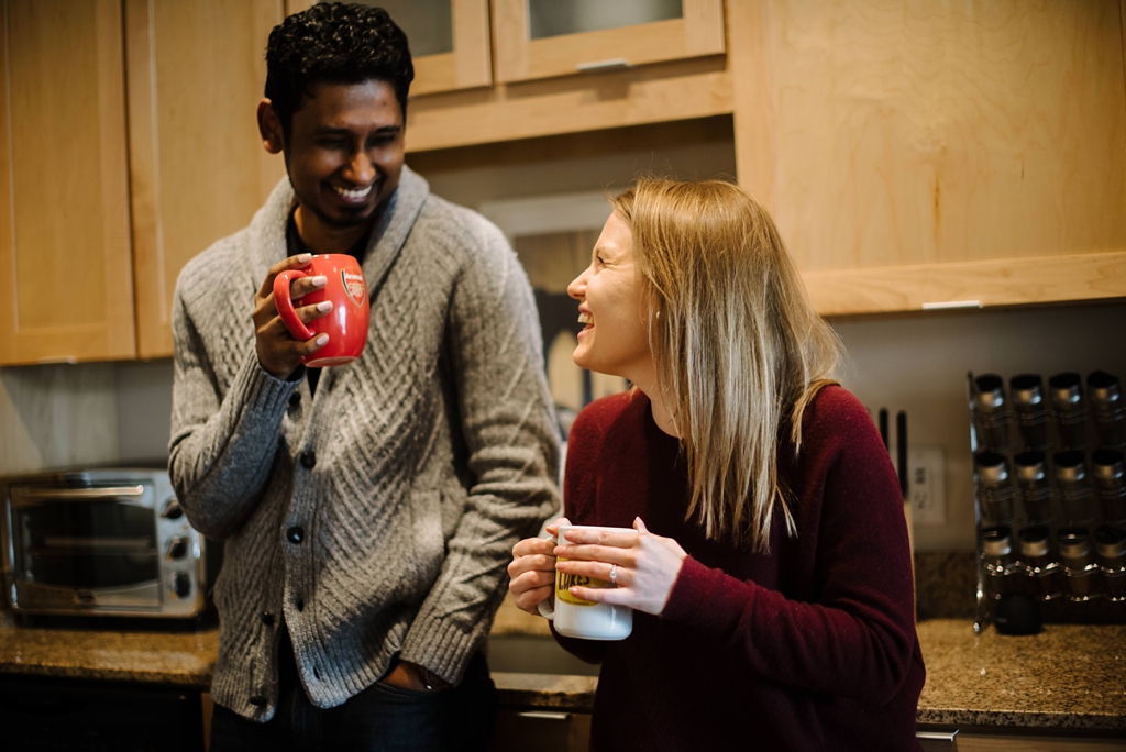 couple laughs and drinks tea together in kitchen