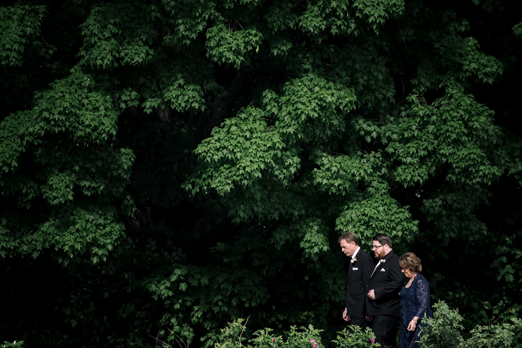 groom walking with parents at outdoor minnesota wedding