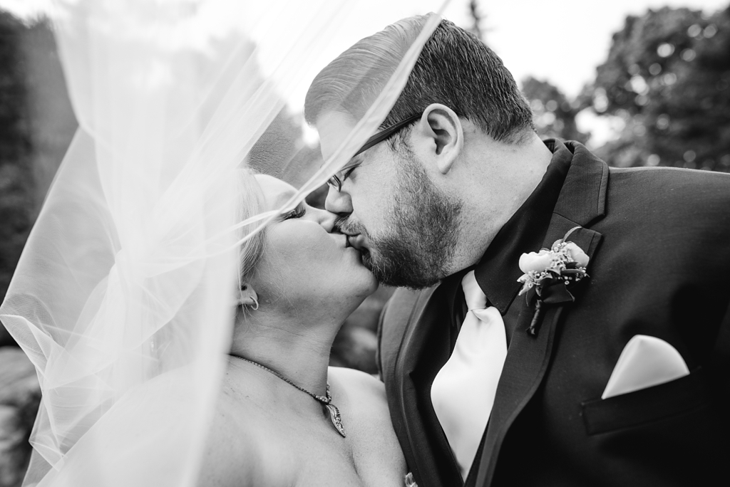 bride and groom kiss beneath veil