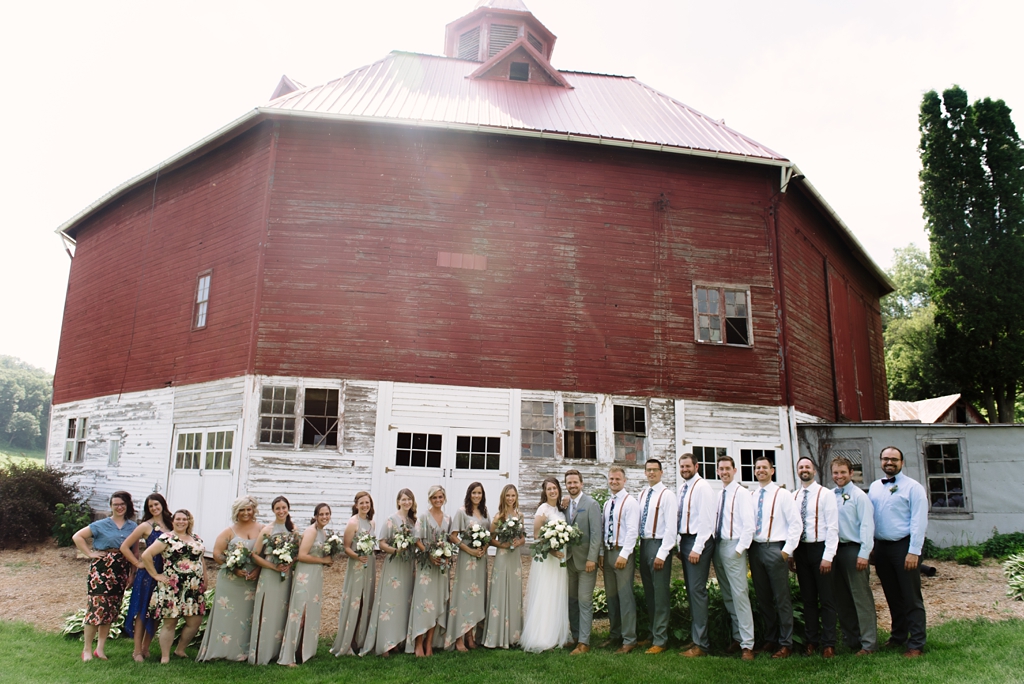 wedding party in front of red barn on wisconsin farm