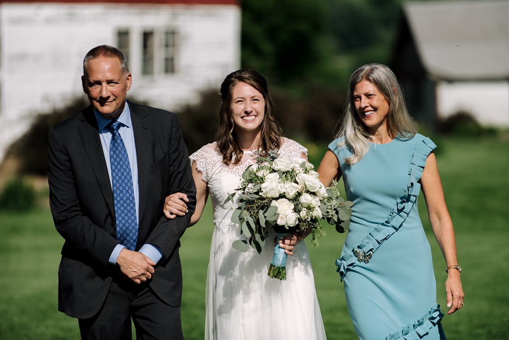 bride escorted by parents in outdoor wedding