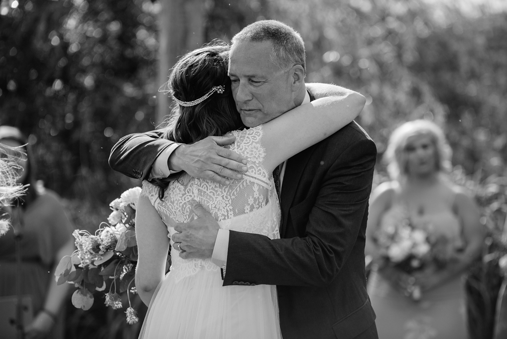 bride hugging father at outdoor ceremony