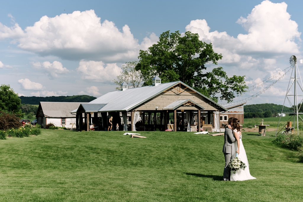 bride and groom kissing in front of farm venue