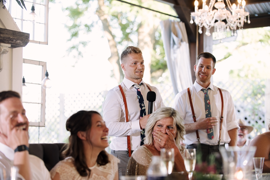 groomsman giving speech while bridesmaid laughs