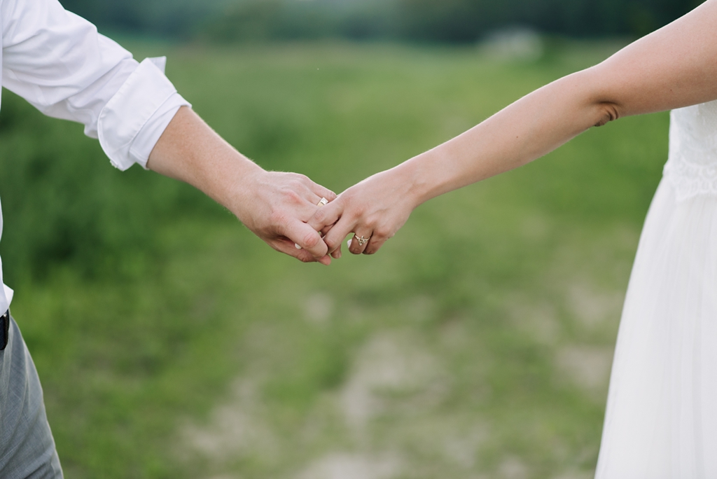 bride and groom holding hands in wisconsin field