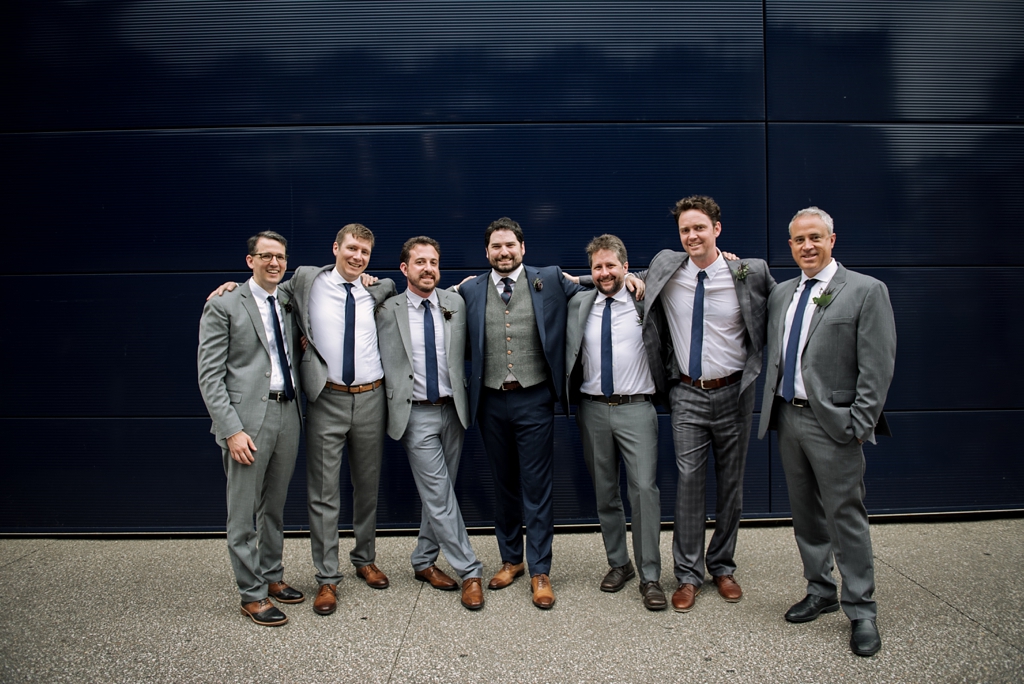 groom and groomsmen pose together outside
