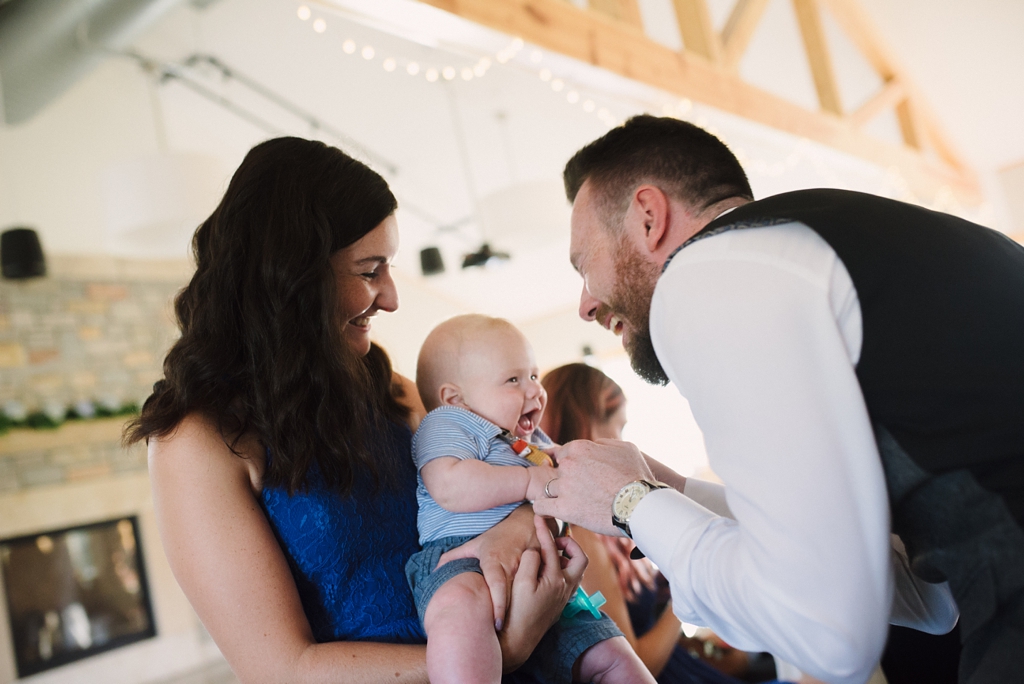 groom laughing with baby at reception