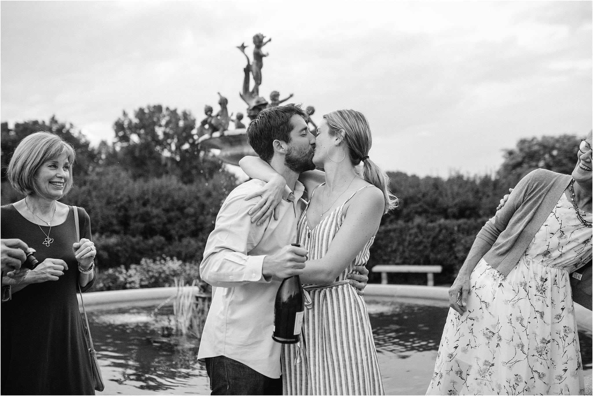 newly engaged couple kisses by fountain