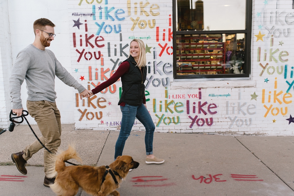 engaged couple walking dog in front of I Like You building