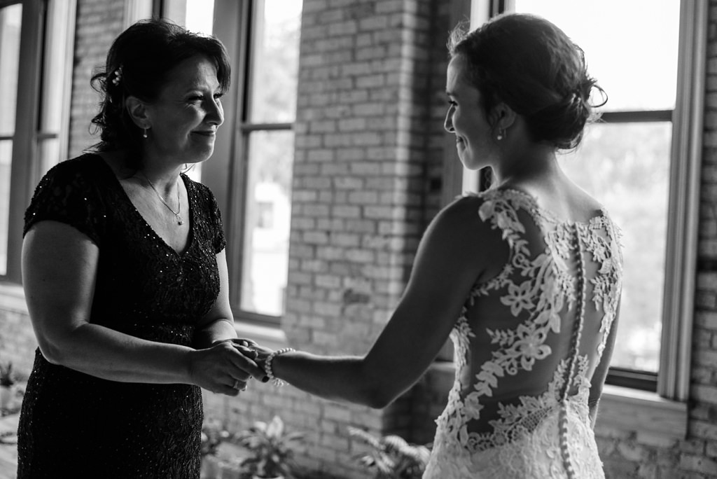 emotional bride and mother hold hands in black and white