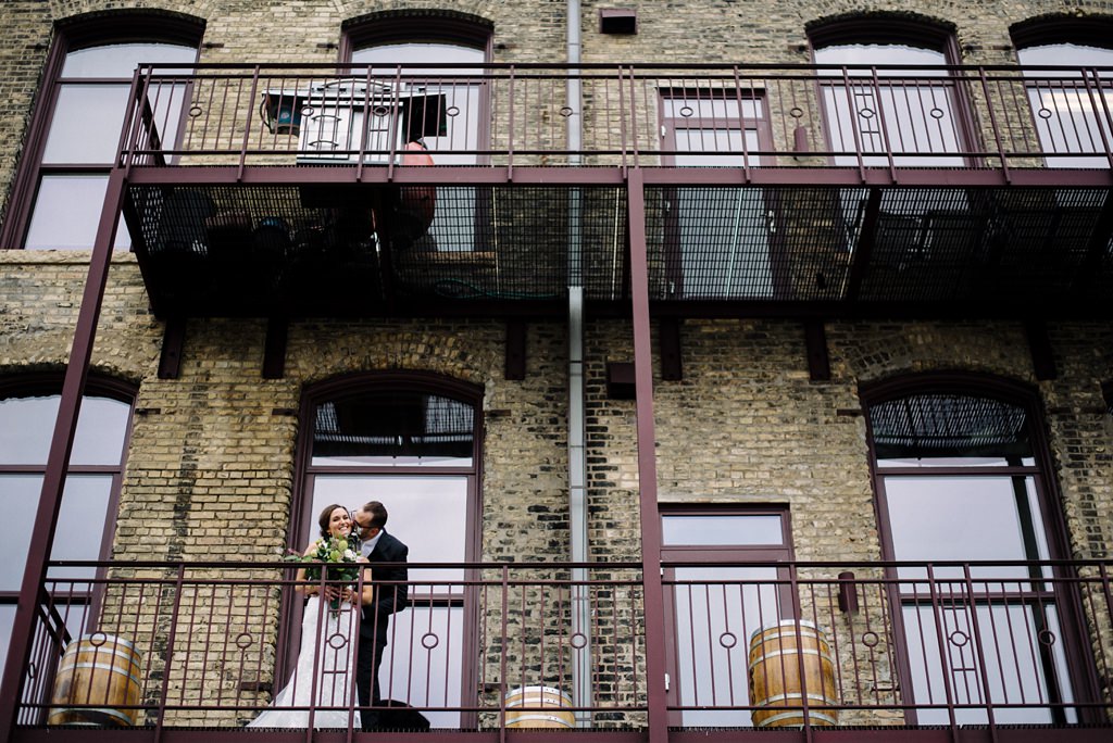 bride and groom embrace on balcony