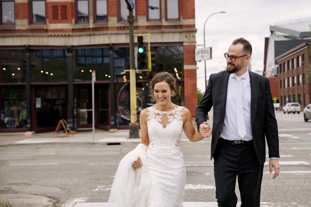 bride and groom holding hands and crossing minneapolis street