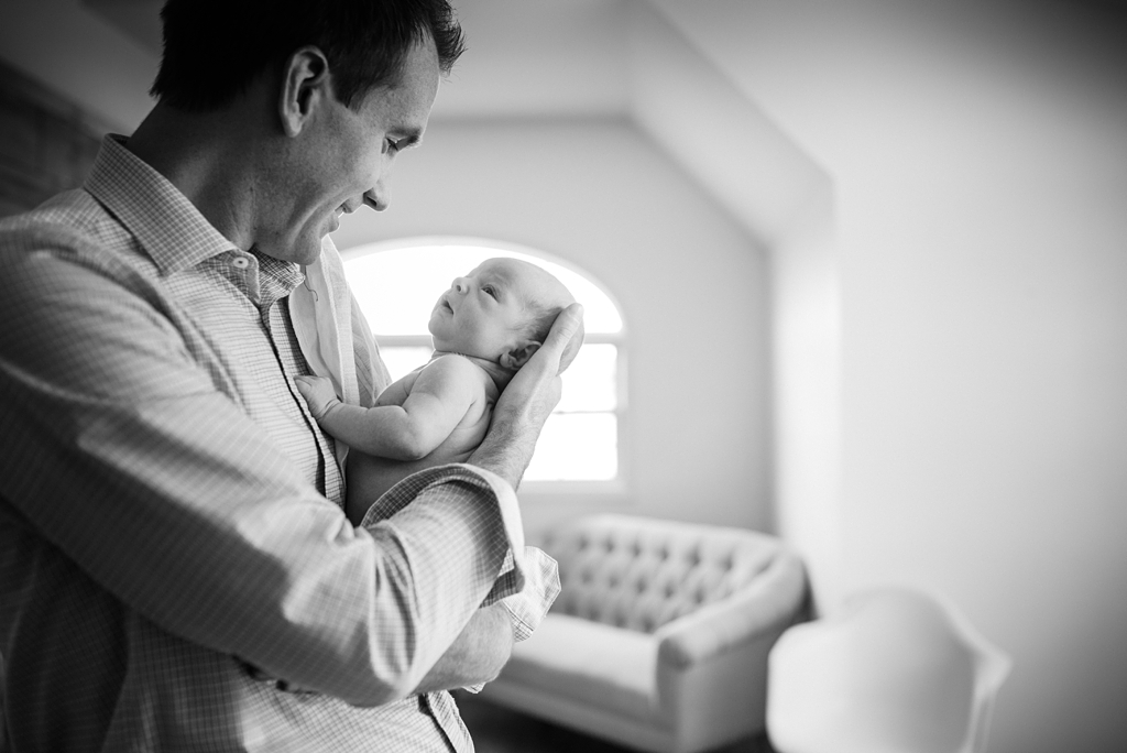 dad holds baby in front of bright window
