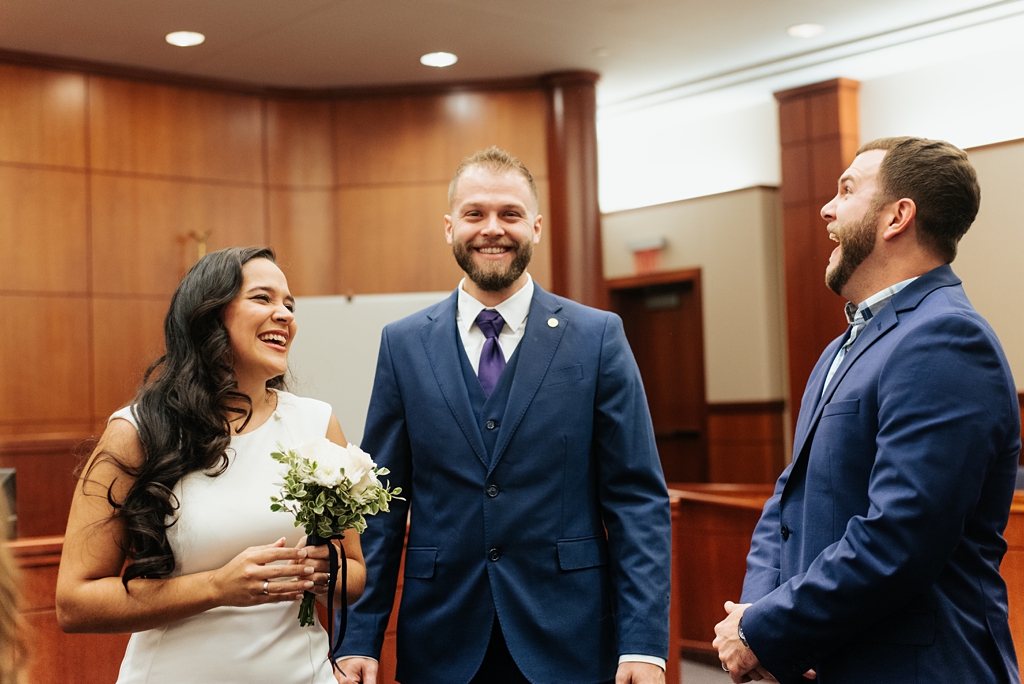 bride and groom laugh with marriage witness