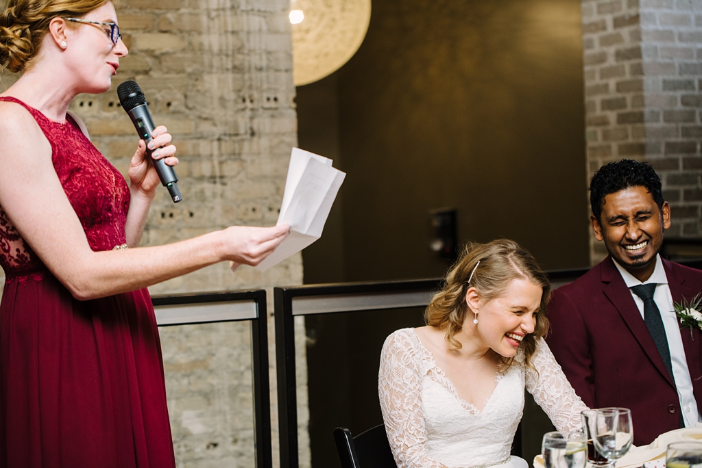 bridesmaid toasts while bride and groom laugh