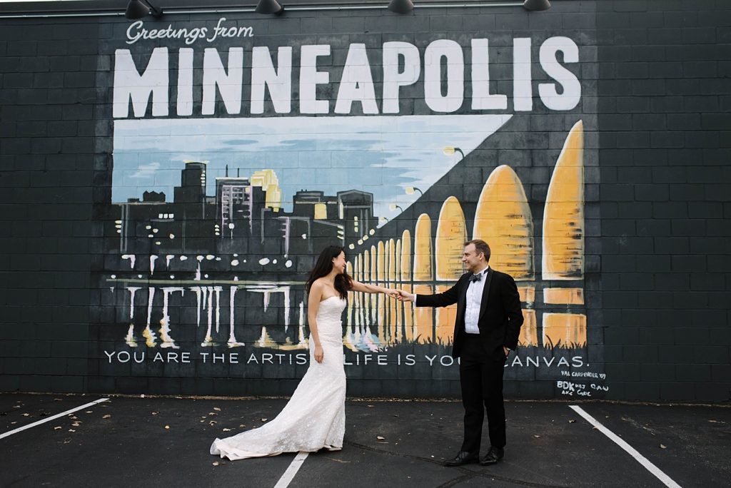 bride and groom with greetings from minneapolis mural downtown